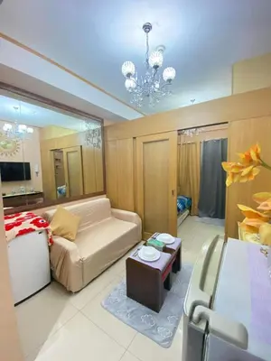 a living room with a couch and a chandelier at Macc Staycation Shell Residences Moa in Manila