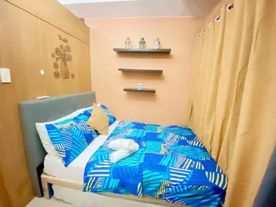 a bedroom with a bed with blue and white sheets at Macc Staycation Shell Residences Moa in Manila
