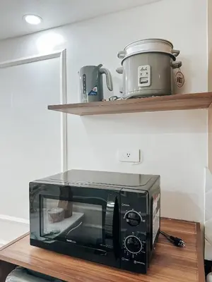 a microwave oven sitting on a wooden shelf at Lian Louise at SMDC Shore 3 MOA with Parking in Manila
