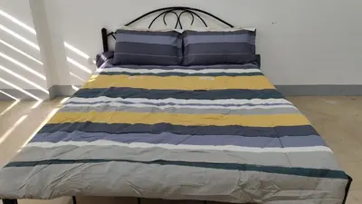 a bed with a blue and yellow striped blanket at V hotel paranaque in Manila