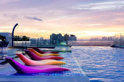 a pool with pink and yellow chairs on the roof of a building at ibis Styles Manila Araneta City in Manila