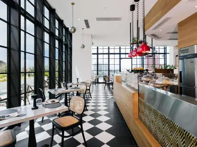 a restaurant with tables and chairs and windows at ibis Styles Manila Araneta City in Manila