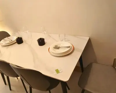 a white table with a plate and glasses on it at ndulge in opulence on a budget near MOA! Luxuriate in our Deluxe 1 Bedroom Units with stunning views. Enjoy free NETFLIX and an exceptional discount. Book now for a lavish and affordable escape! in Manila
