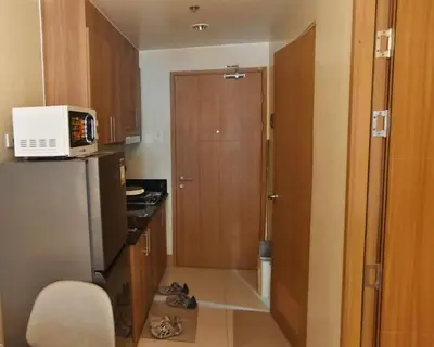 a small kitchen with a refrigerator and a microwave at ndulge in opulence on a budget near MOA! Luxuriate in our Deluxe 1 Bedroom Units with stunning views. Enjoy free NETFLIX and an exceptional discount. Book now for a lavish and affordable escape! in Manila