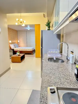a kitchen with a sink and a living room at 1 BR Uptown BGC Cozy Condo Netflix 200Mb Wi-Fi in Manila