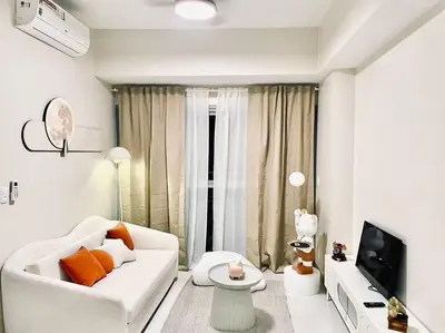 a white living room with a white couch and a tv at Thompson Suites - 2-beds near OKADA, Bayshore 2 in Manila