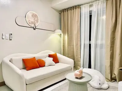 a living room with a white couch with orange pillows at Thompson Suites - 2-beds near OKADA, Bayshore 2 in Manila