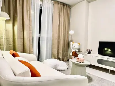 a living room with a white couch and a tv at Thompson Suites - 2-beds near OKADA, Bayshore 2 in Manila