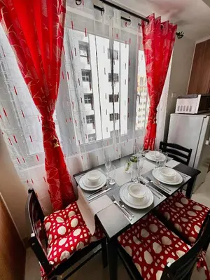 a dining room table with red curtains and a table and chairs at Apartment Seaside Bliss in Manila