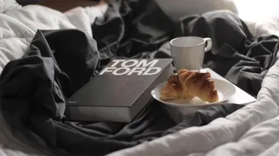 a plate of food and a book and a cup on a bed at Avida Sucat Tower 9 in Manila