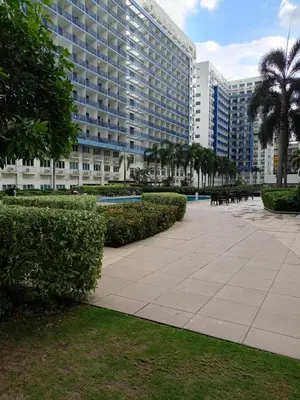 a large building with palm trees in a park at Kings staycation at mall of asia in Manila