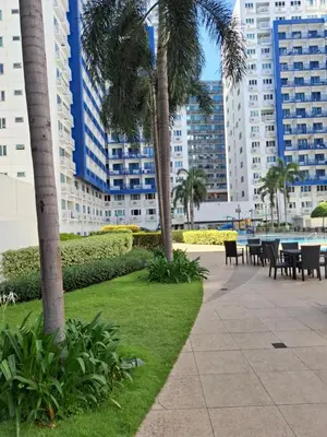 a park with tables and palm trees and buildings at Kings staycation at mall of asia in Manila