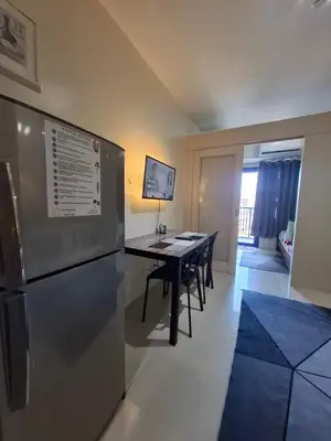 a kitchen and dining room with a table and a refrigerator at Kings staycation at mall of asia in Manila