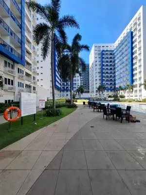 a park with tables and chairs and palm trees and buildings at Kings staycation at mall of asia in Manila