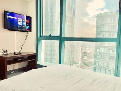 a bedroom with a bed and a large window at Thompson Suites Queen Room, One Uptown Residences, XBOX & Netflix in Manila