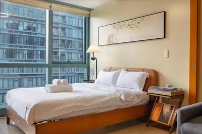 a bedroom with a bed and a large window at Thompson Suites Queen Room, One Uptown Residences, XBOX & Netflix in Manila