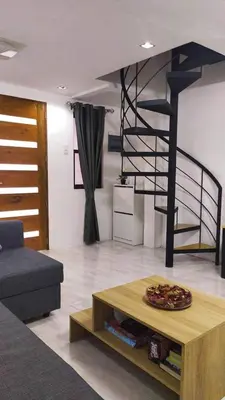 a living room with a table and a spiral staircase at Saphir Townhouse 5 to 6 pax rooftop terrace, Cavite in Imus