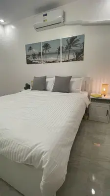 a bedroom with a large white bed with palm trees on the wall at Saphir Townhouse 5 to 6 pax rooftop terrace, Cavite in Imus