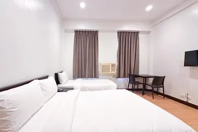 a hotel room with two beds and a desk at SANTOS Pension House in Manila