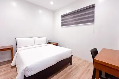 a bedroom with a bed and a desk and a window at SANTOS Pension House in Manila