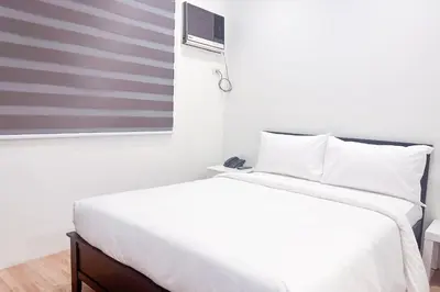 a bedroom with a white bed and a window at SANTOS Pension House in Manila