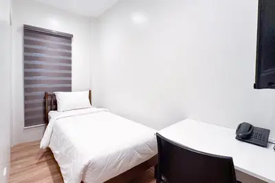 a bedroom with two beds and a desk with a telephone at SANTOS Pension House in Manila
