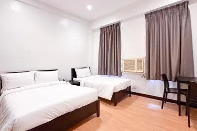 a hotel room with two beds and a desk at SANTOS Pension House in Manila