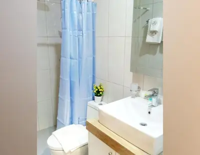 a bathroom with a sink and a toilet and a blue shower curtain at AMORE HOTEL MANILA in Manila