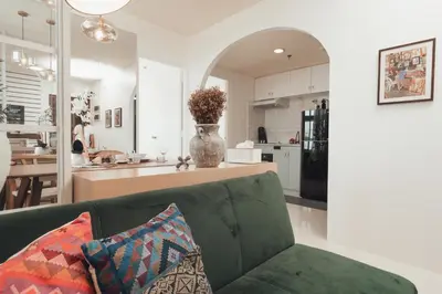 a living room with a green couch and a kitchen at Modern Luxe Condo Unit in Cavite in Imus