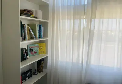 a book shelf with a white curtain and a window at Modern Luxe Condo Unit in Cavite in Imus