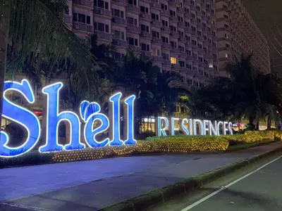 a lit up sign for a hotel at night at Aiza's Place in Shell Residences MOA in Manila