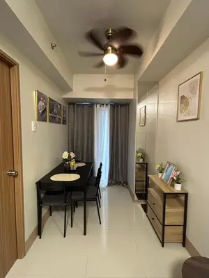 a living room with a dining room table and a ceiling fan at JN Staycation at Shore 3 Mall of Asia in Manila