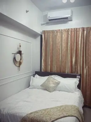 a bed with white sheets and pillows in a bedroom at Mid-Century Extent Condo Unit @ Shore 2, MOA in Manila