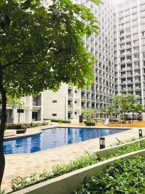 a large building with a swimming pool in front of it at Mid-Century Extent Condo Unit @ Shore 2, MOA in Manila