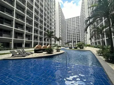 a large swimming pool with chairs and a building at Mid-Century Extent Condo Unit @ Shore 2, MOA in Manila