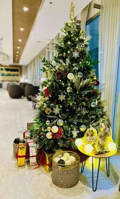 a christmas tree in a lobby with presents under it at Mid-Century Extent Condo Unit @ Shore 2, MOA in Manila
