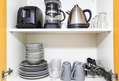 a cupboard with dishes and a coffee maker and plates at Executive Suite - BSA Twin Towers, Ortigas Ctr in Manila