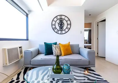 a living room with a couch and a clock on the wall at Executive Suite - BSA Twin Towers, Ortigas Ctr in Manila