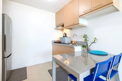 a kitchen with a white table and blue chairs at Executive Suite - BSA Twin Towers, Ortigas Ctr in Manila