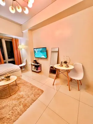 a room with a bed and a table and a tv at Mandaluyong Staycation in Manila