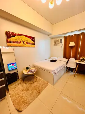 a bedroom with a bed and a table and a tv at Mandaluyong Staycation in Manila