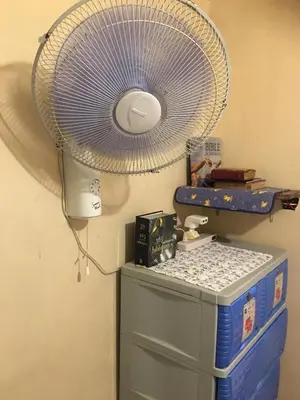 a white fan hanging from a wall above a dresser at Guesthouse Cavite in Dasmariñas