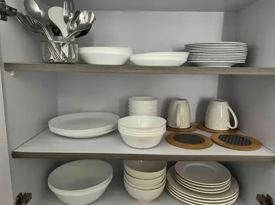 a shelf filled with white plates and bowls and utensils at Penthouse Condo Unit near Airport NAIA in Manila