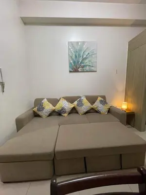 a living room with a couch with pillows on it at Shore Residence Mall of Asia Direct pool in Manila
