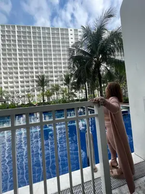 a woman standing on a balcony looking at a pool at Shore Residence Mall of Asia Direct pool in Manila