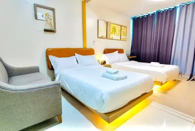 a hotel room with two beds and a chair at Thompson Suites - 2 beds, One Uptown Residences - XBOX & Netflix in Manila