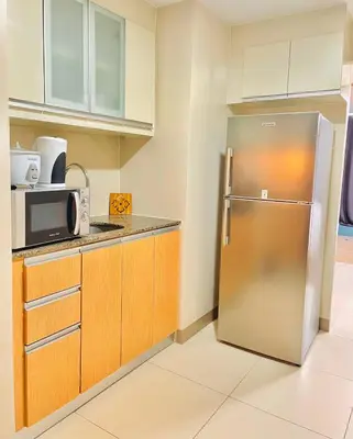 a kitchen with a stainless steel refrigerator and cabinets at Thompson Suites - 2 beds, One Uptown Residences - XBOX & Netflix in Manila