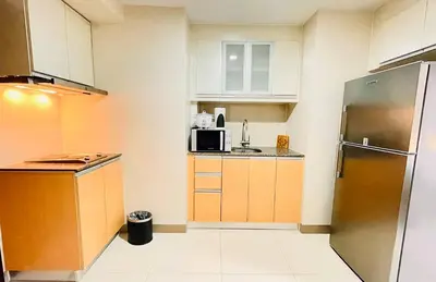 a small kitchen with a refrigerator and a microwave at Thompson Suites - 2 beds, One Uptown Residences - XBOX & Netflix in Manila