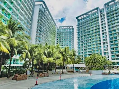 a swimming pool with palm trees and tall buildings at Azure Condo 1BR Next to Mall, Near City & Airport in Manila
