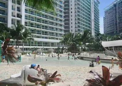 a man sitting in a chair on a beach at Azure Condo 1BR Next to Mall, Near City & Airport in Manila
